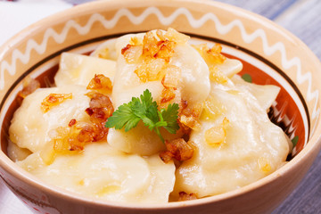 Varenyky, vareniki, pierogi, pyrohy or dumplings, filled with potato and served with salty caramelized onion