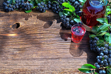 A glass of tincture of chokeberry. Free space for your text. Wooden background.