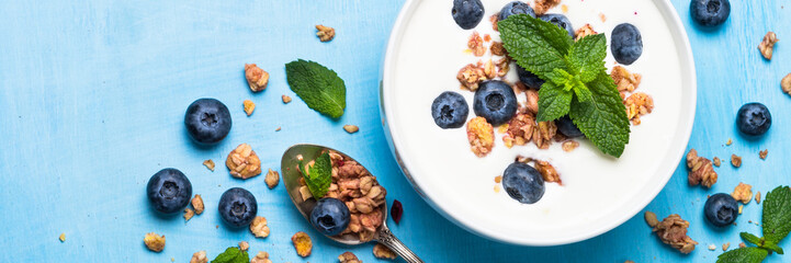 Greek yogurt granola and blueberries on blue table. Top view.