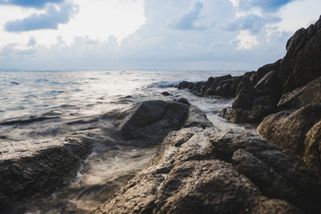 Tropical beach with rock and sea water in sunrise scene.