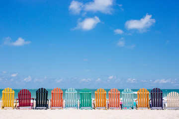 Colorful chairs on the white sand beach with clouds on the blue sky background - 168072311