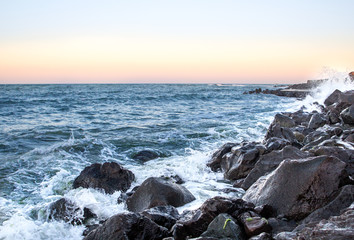 Sea waves in sunset with rocks and stones. Nature landscape.