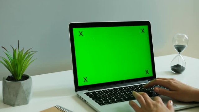 Business woman working on the laptop with green screen in the office. Chroma key. Tracking motion. Side view.