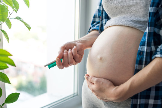 Pregnant woman belly holding a cigarette and a lighter. Concept of Smoking and bad habits during pregnancy