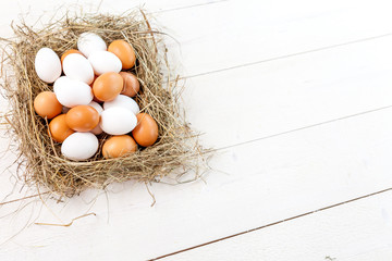 Fresh country eggs with straw on rustic wooden table, free space