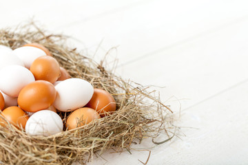 Fresh country eggs with straw on rustic wooden table, free space