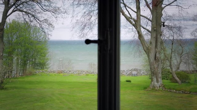 Room with a view from window over a green garden and the sea.
