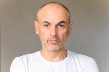 Obraz premium Gray-haired adult unshaven man with blue eyes in a white tank top on a gray background