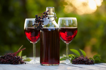 Bottle and glasses of elderberry wine on wooden table