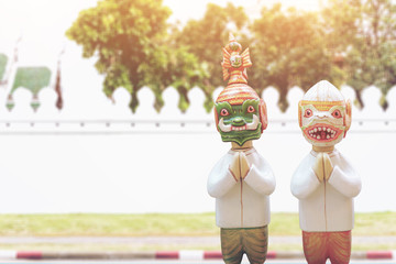 Obraz premium Doll Hanuman and Thotsakan respect hands sawasdee and uniform thai style with image blur wall of temple thailand.