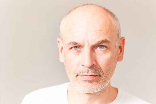 Gray-haired Adult Unshaven Man With Blue Eyes In A White Tank Top On A Gray Background