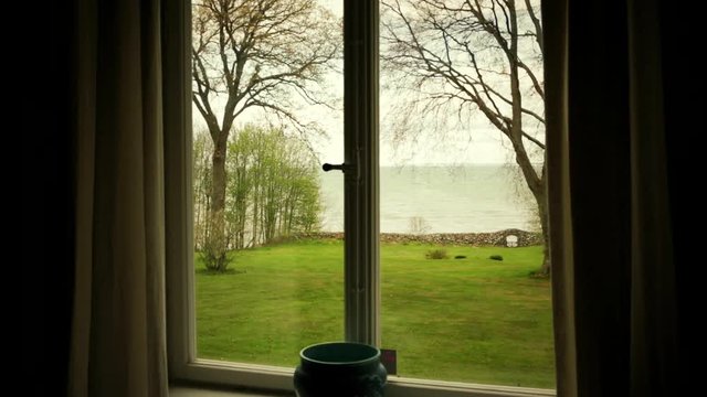 View from window. Room with a view from window over a green garden and the sea.
