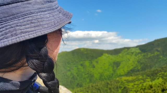 the girl in the hat and pigtails looks at the landscape of the mountains