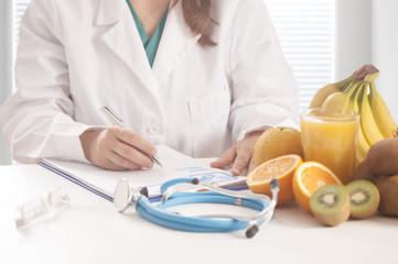 Nutritionist writing medical records and prescriptions with fresh fruits
