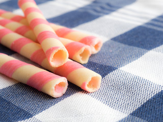 pink striped wafer rolls on blue plaid tablecloth.