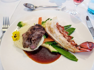 filet mignon steak and lobster tail with colorful vegetables on dinner plate