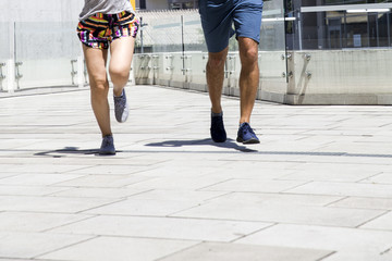 Handsome man and beautiful woman jogging together on street between residential buildings
