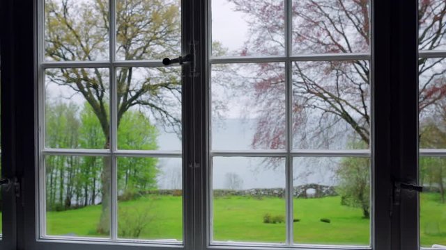 View from old summerhouse. Framed window Beautiful view over garden and sea. Camera travel right to left.