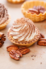 Delicious mini tarts with whipped cream and pecans. Close up.