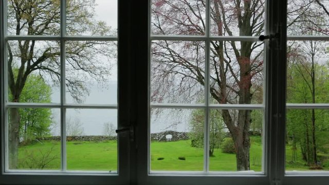 View from window over a green garden and the sea.Camera travel left to right.
