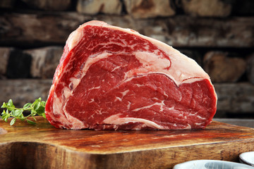 Raw fresh meat Ribeye Steak, seasoning and meat fork on dark background