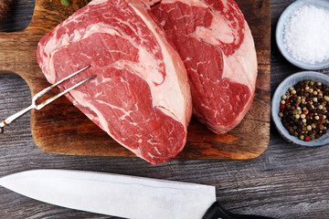 Raw fresh meat Ribeye Steak, seasoning and meat fork on dark background