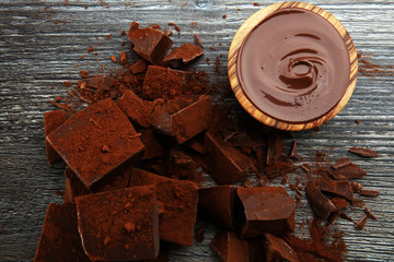 Chocolate cream melted, chocolate pieces and chocolate powder on wooden table