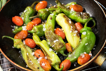 Eine Pfanne mit gebratenen Paprika, Peperoni und Kirchtomaten mit Meersalz