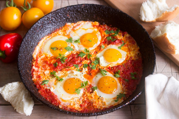 Shakshuka with bread on a wooden table. Middle eastern traditional dish. Homemade. Selective focus.