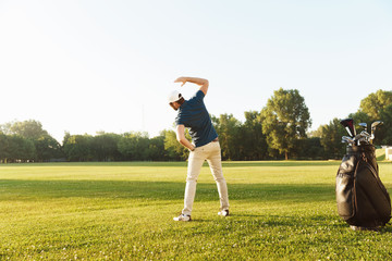 Young male golfer stretching muscles before starting the game