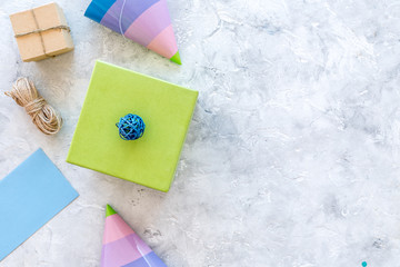 Preparing to celebration. Colored gift boxes and party hats on grey stone background top view copyspace