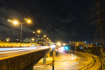 Fototapeta na wymiar motion blurred and light trail of car on and under the rama 7 bridge with dark sky and cloud