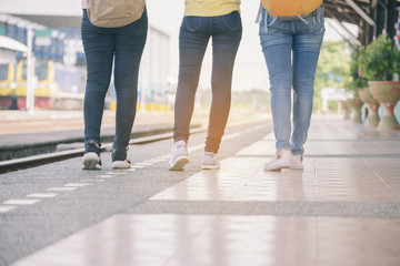 Group of beautiful traveler woman (friends),wearing fashion jeans and sneaker.Close up of feet's backpacker women walking at train station.Travel concept.