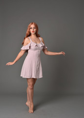 Naklejka premium full length portrait of pr a pretty girl wearing simple purple dress, standing pose against a grey background