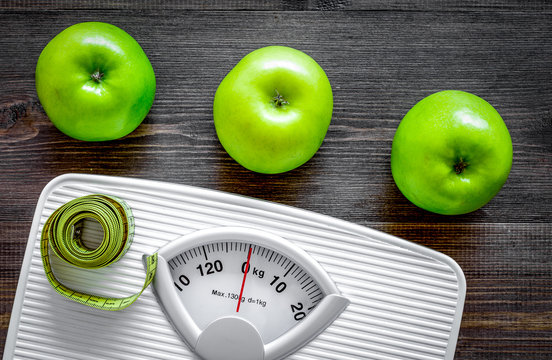 Lose weight concept. Bathroom scale, measuring tape, apples on wooden background top view