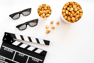 To go to the cinema. Clapperboard, glasses and popcorn on white background top view copyspace