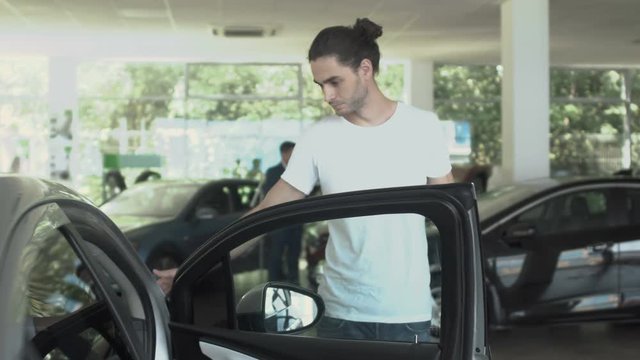 Handsome man inspects the car in car dealership