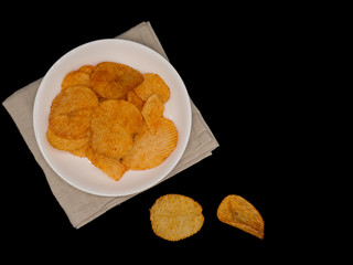Potato chips on white dish,black background with copy space