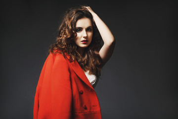 Beautiful young woman posing in studio over grey background. Fashion concept.