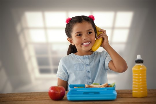 Composite image of smiling girl using banana as phone