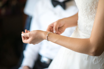 Obraz na płótnie Canvas Bride's hand Put the bracelet
