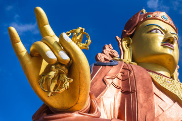 Close up at the right golden hand with mace and head of Guru Rinpoche statue, the patron saint of...