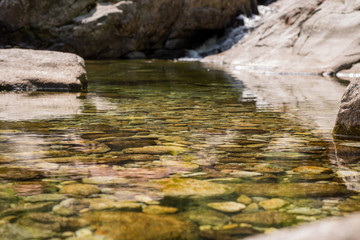 Colorfull mountain crystal pond on a river near a little waterfall in the morning in summer outdoor.