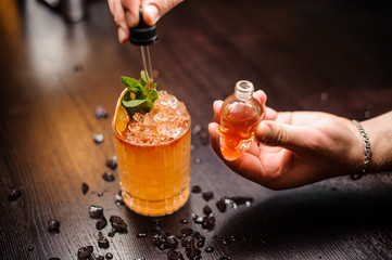 small skull-shaped bottle, summer cocktail and barmen hand