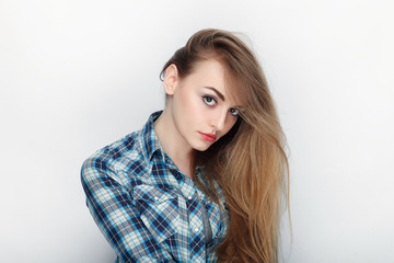 Beauty portrait of young adorable fresh looking blonde woman with hair chaos in blue plaid shirt. Emotion and facial expression concept.