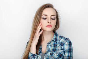 Beauty portrait of young adorable fresh looking blonde woman with hair chaos in blue plaid shirt. Emotion and facial expression concept.