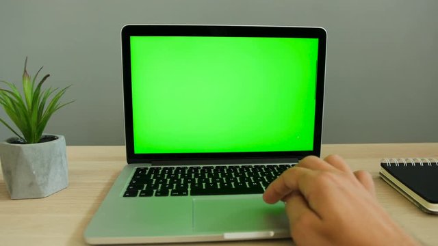 Man hands typing on laptop with green screen at the office table. Chroma key. Close up shot.