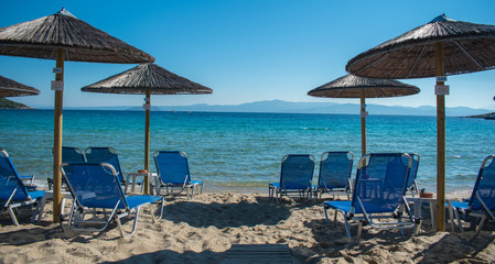 Sun chairs on the beach with sea in background. Summer holiday / vacation. Xenia Golden Beach, Paliouri, Chalkidiki, Greece on a beautiful summer day