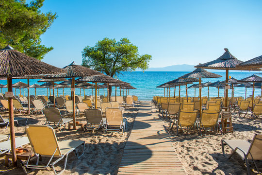 Sun chairs on the beach with sea in background. Summer holiday / vacation. Xenia Golden Beach, Paliouri, Chalkidiki, Greece on a beautiful summer day