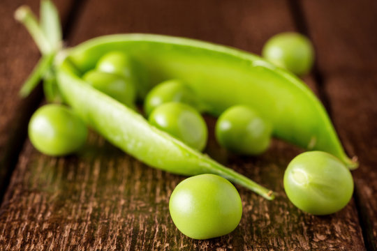 Fresh green pea pod and peas on dark wooden background